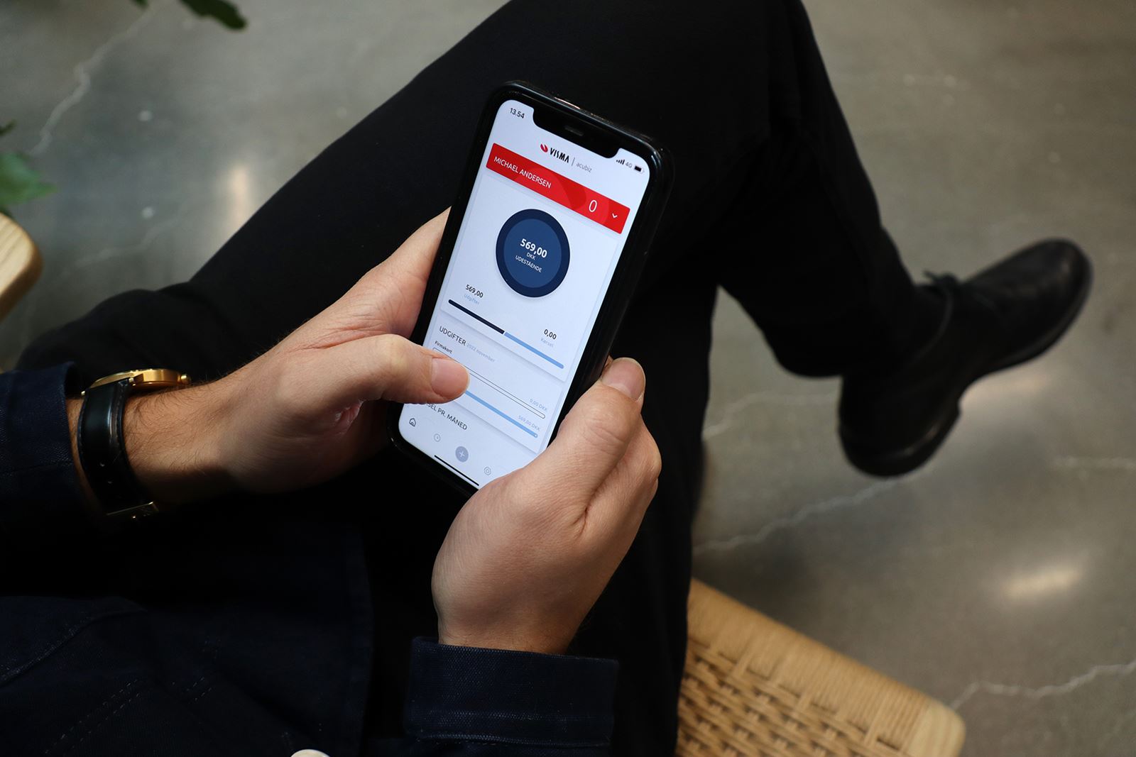 person sidder med mobil og kigger på Visma Acubiz til din virksomhed