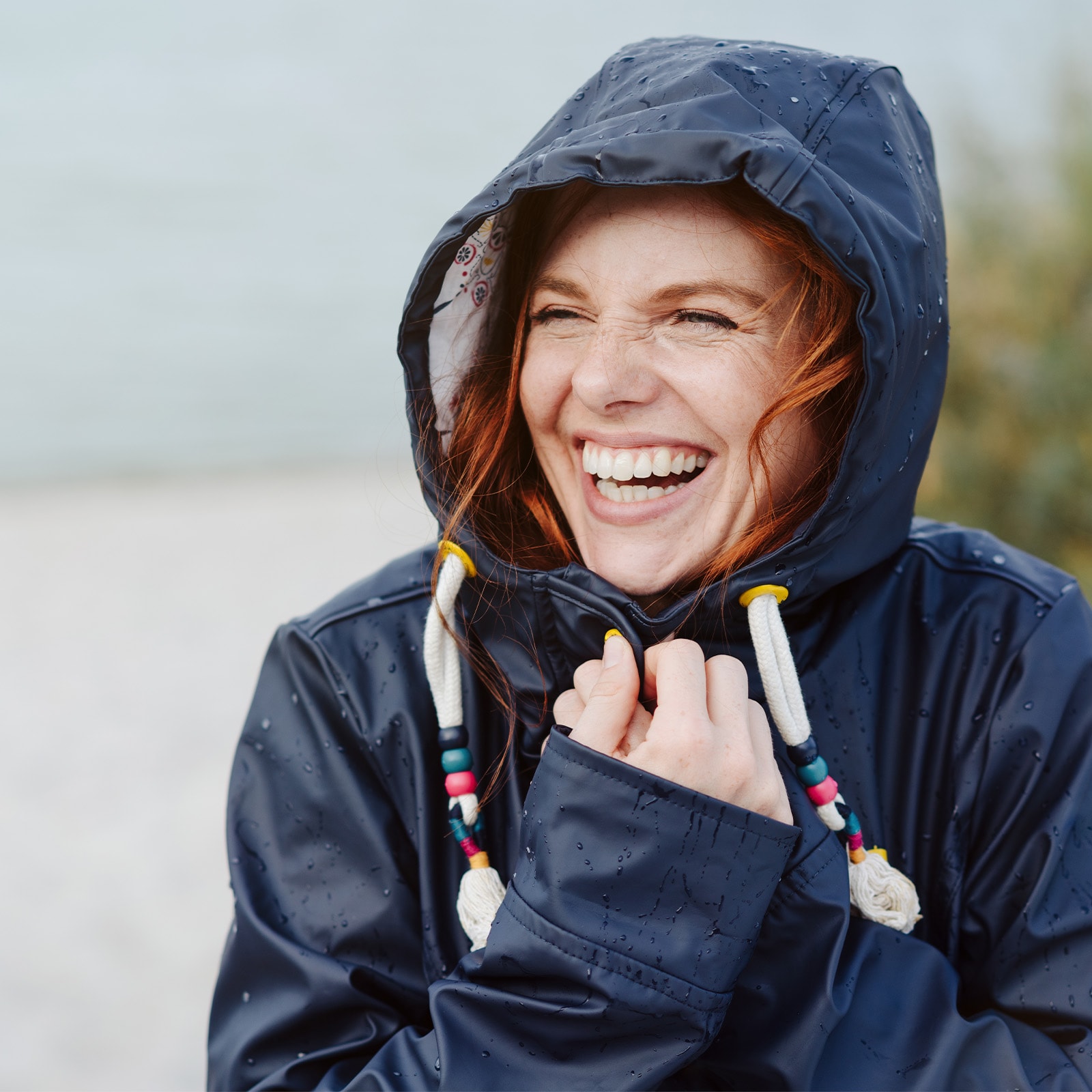 Person i regnjakke ved kysten.