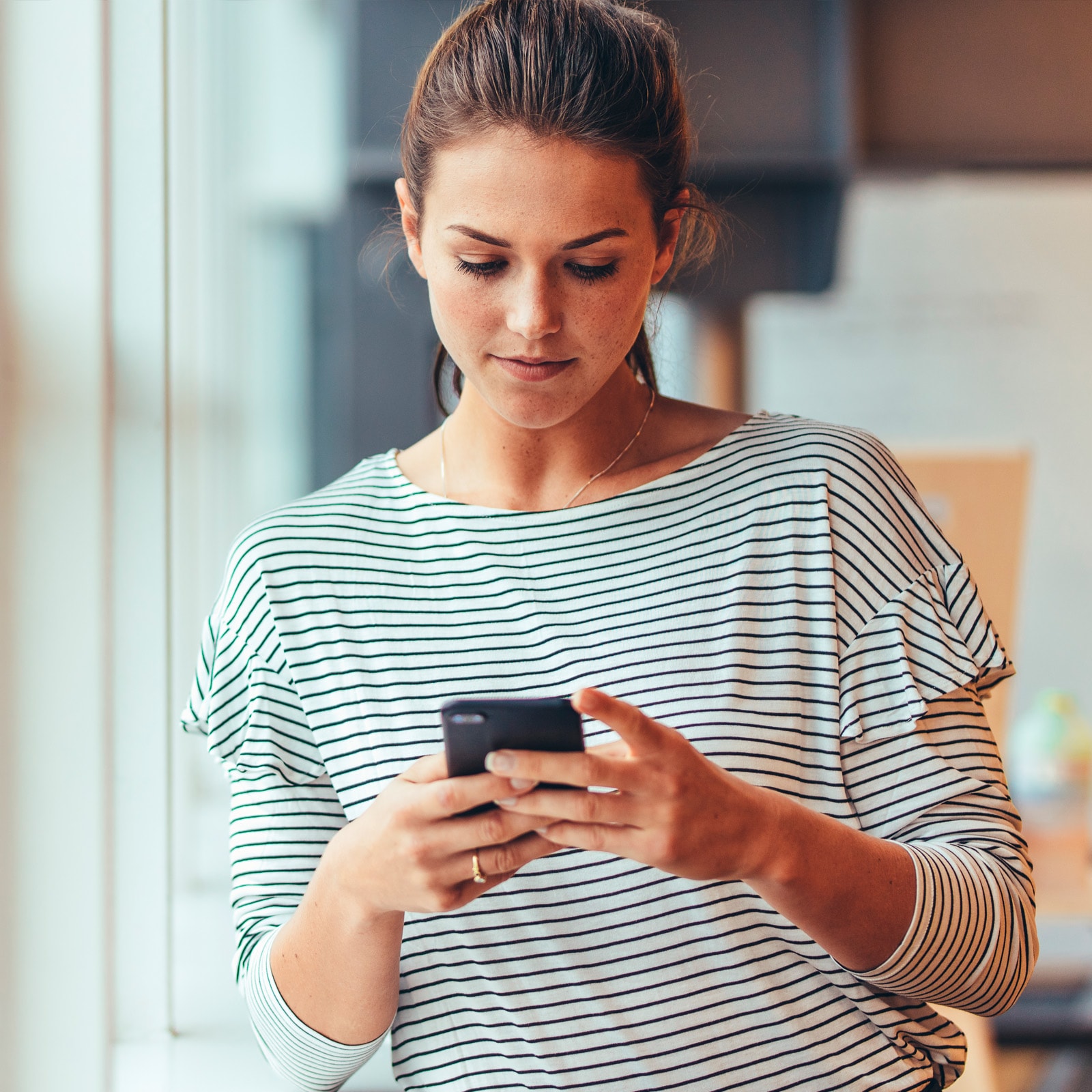 Person bruger smartphone i hjemlige omgivelser.