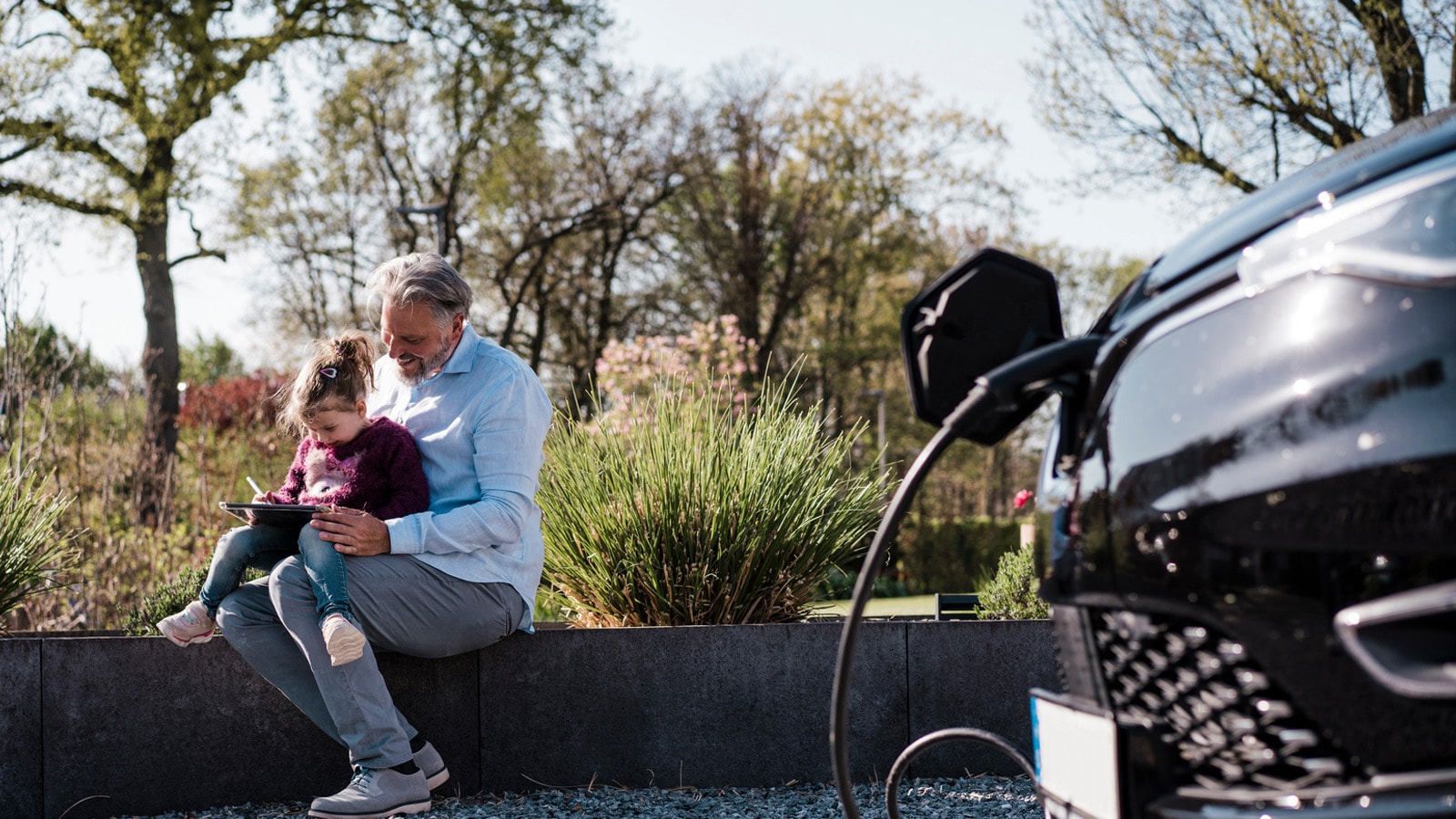 Elbil lader mens far og datter tager en siddende pause udenfor