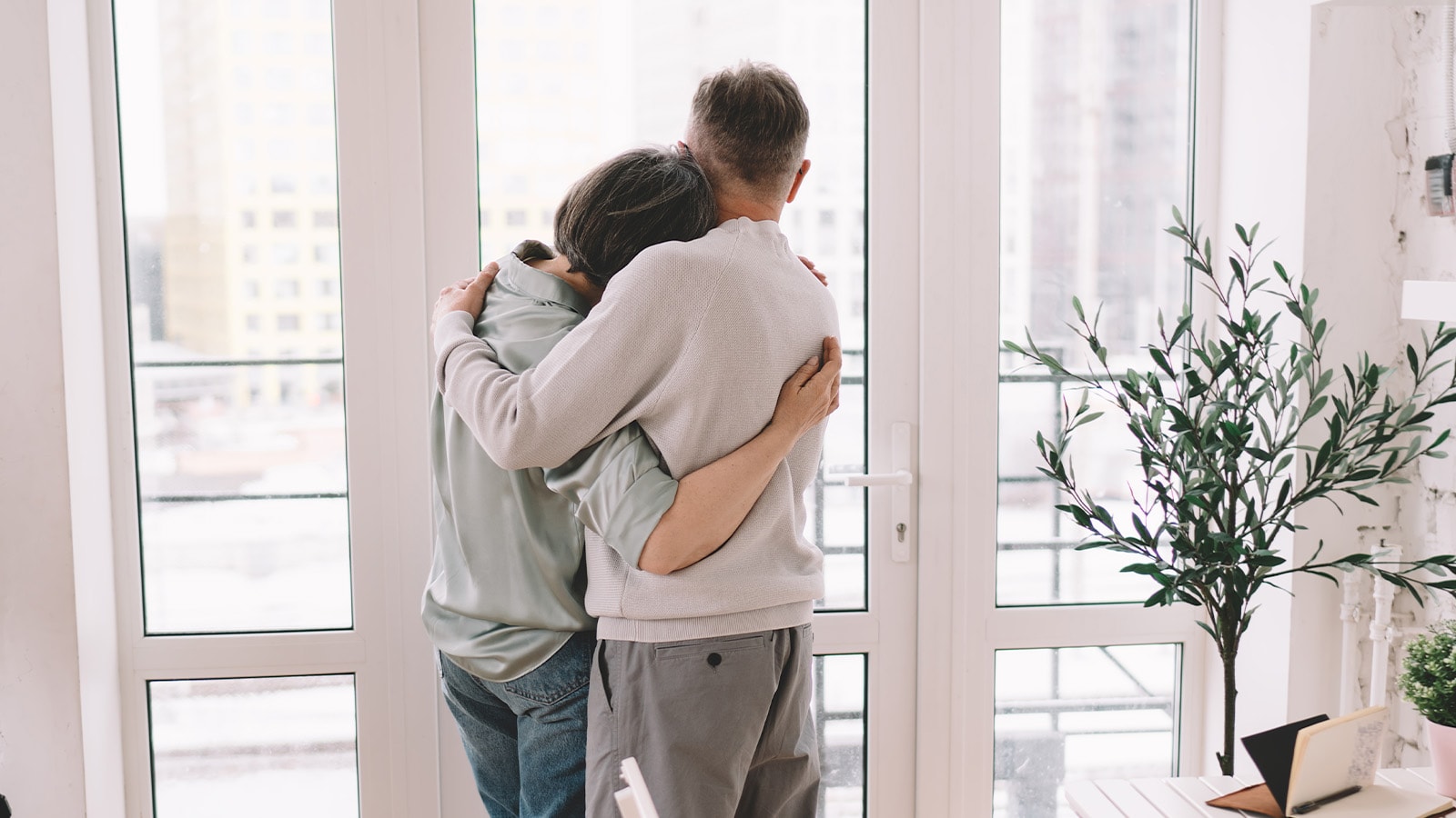 Par står i stue ved terrassedør og kigger ud af døren