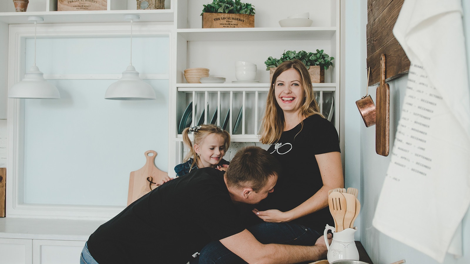 Lille familie med gravid mor, far og pige sidder i køkkenet