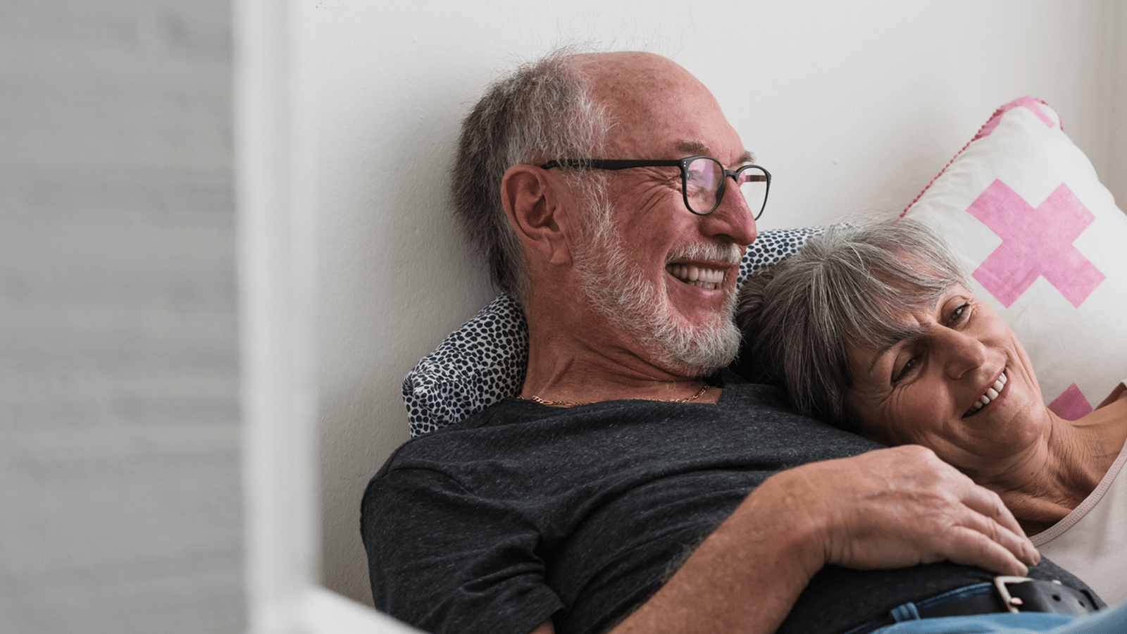 Ældre par ligger i sengen og smiler