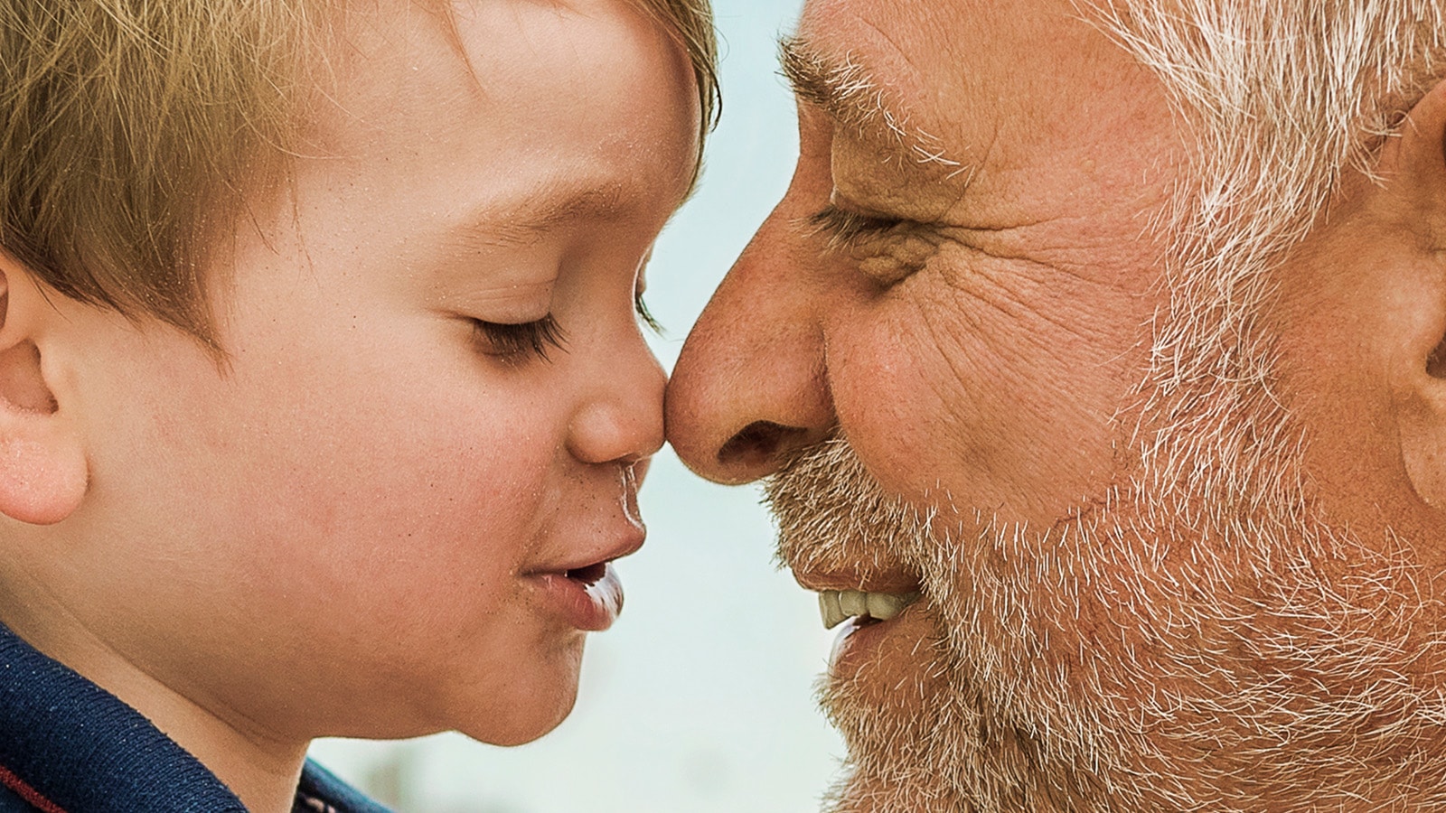 Bedstefar og barnebarn kigger smilende mod hinanden mens deres næser mødes