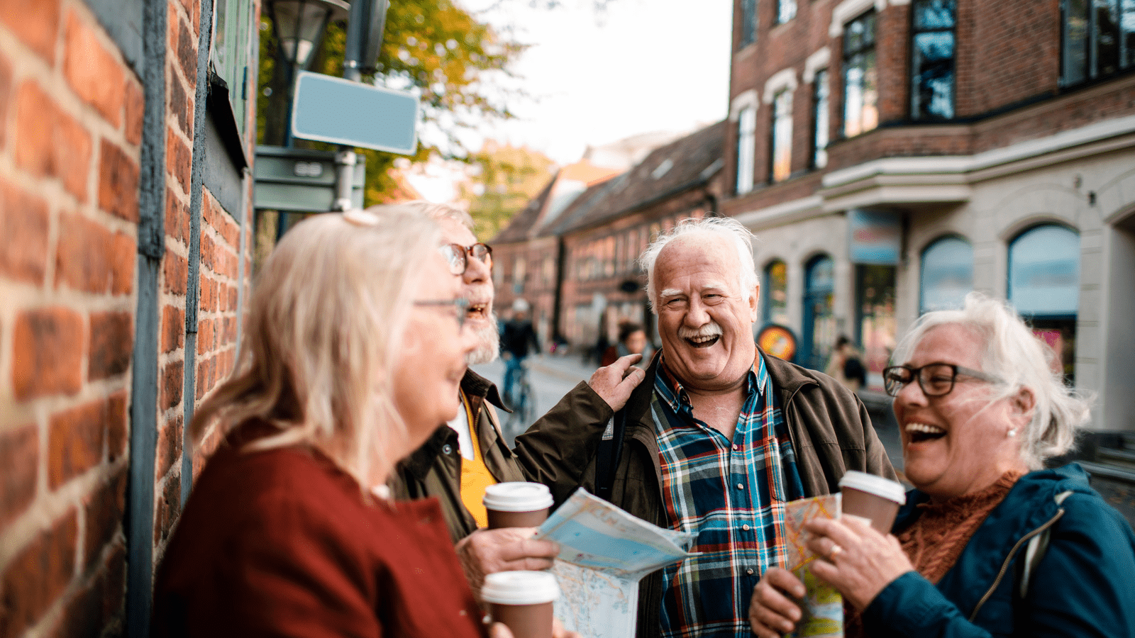 Glade pensionister på tur i byen griner til hinanden med kaffe i hånden