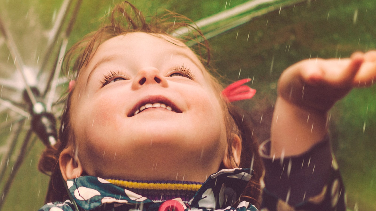 Lille dreng ligger på græsplænen og kigger smilende op 