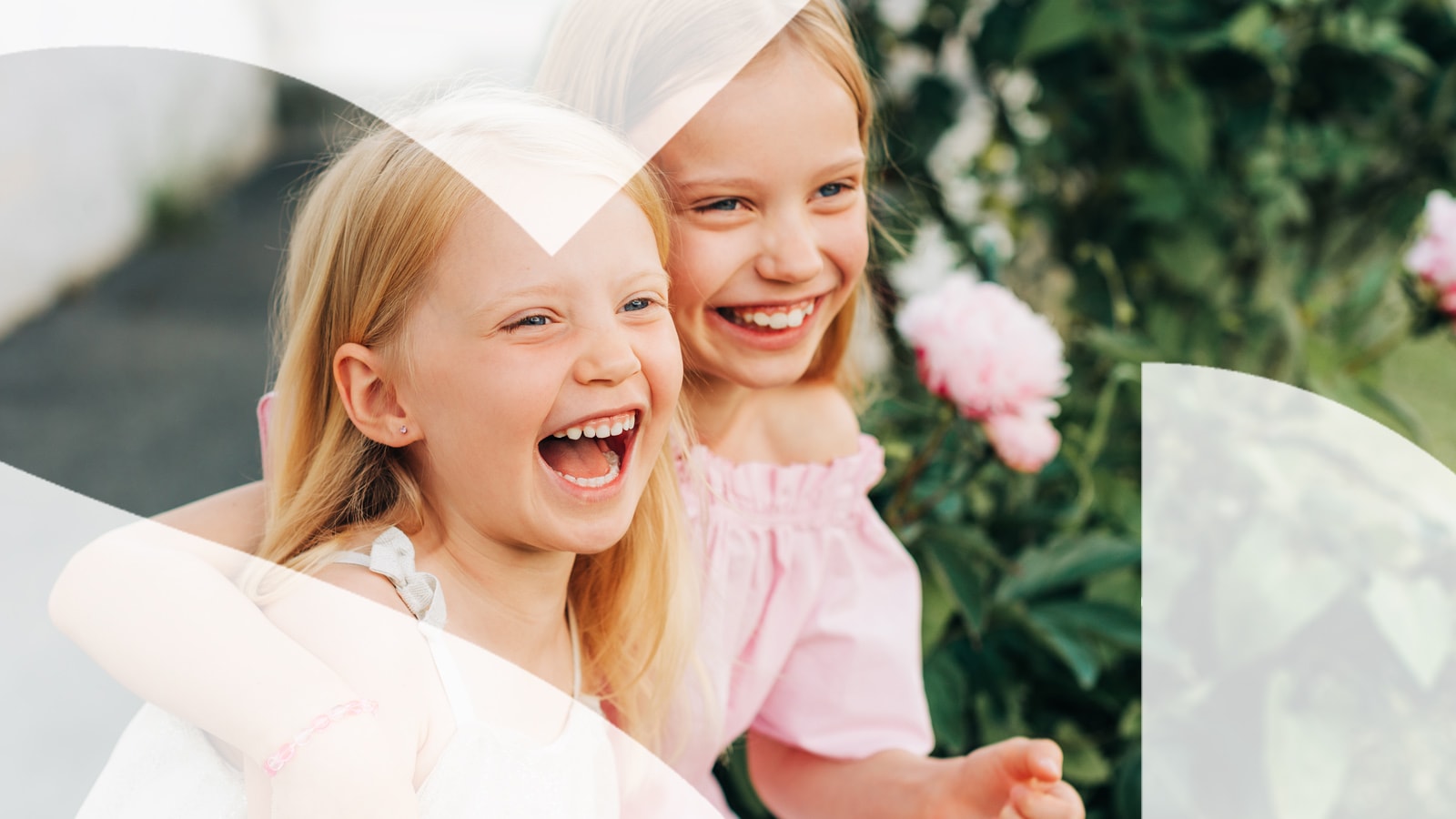 To glade, små, piger sidder sammen og griner ud i horisonten