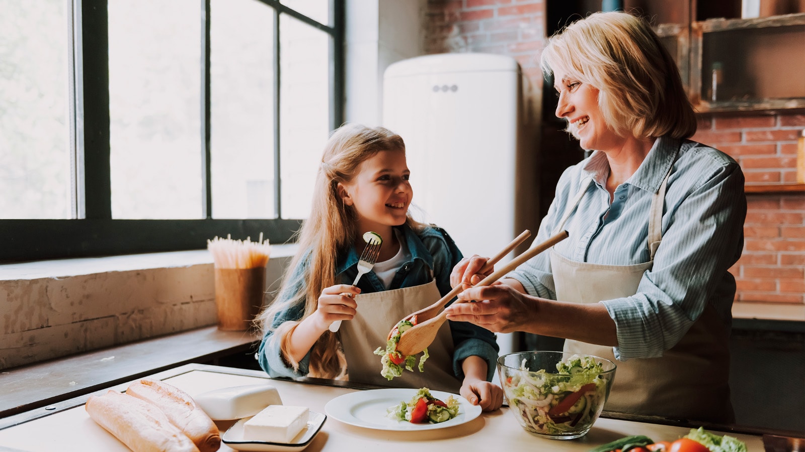 bedstemor og barnebarn spiser mad sammen og smiler til hinanden
