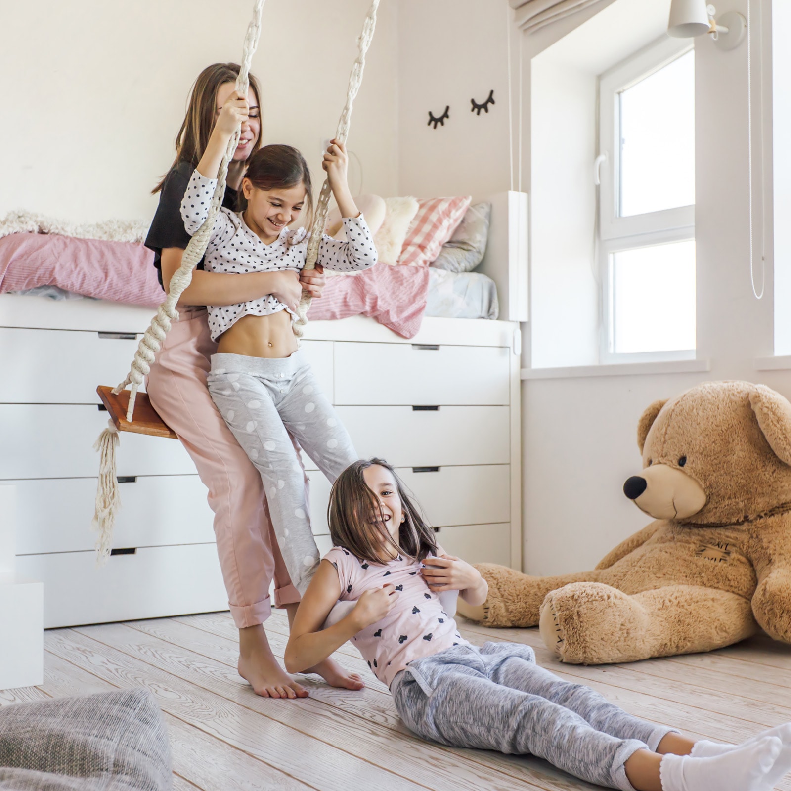 Mor og to piger gynger på børneværelset