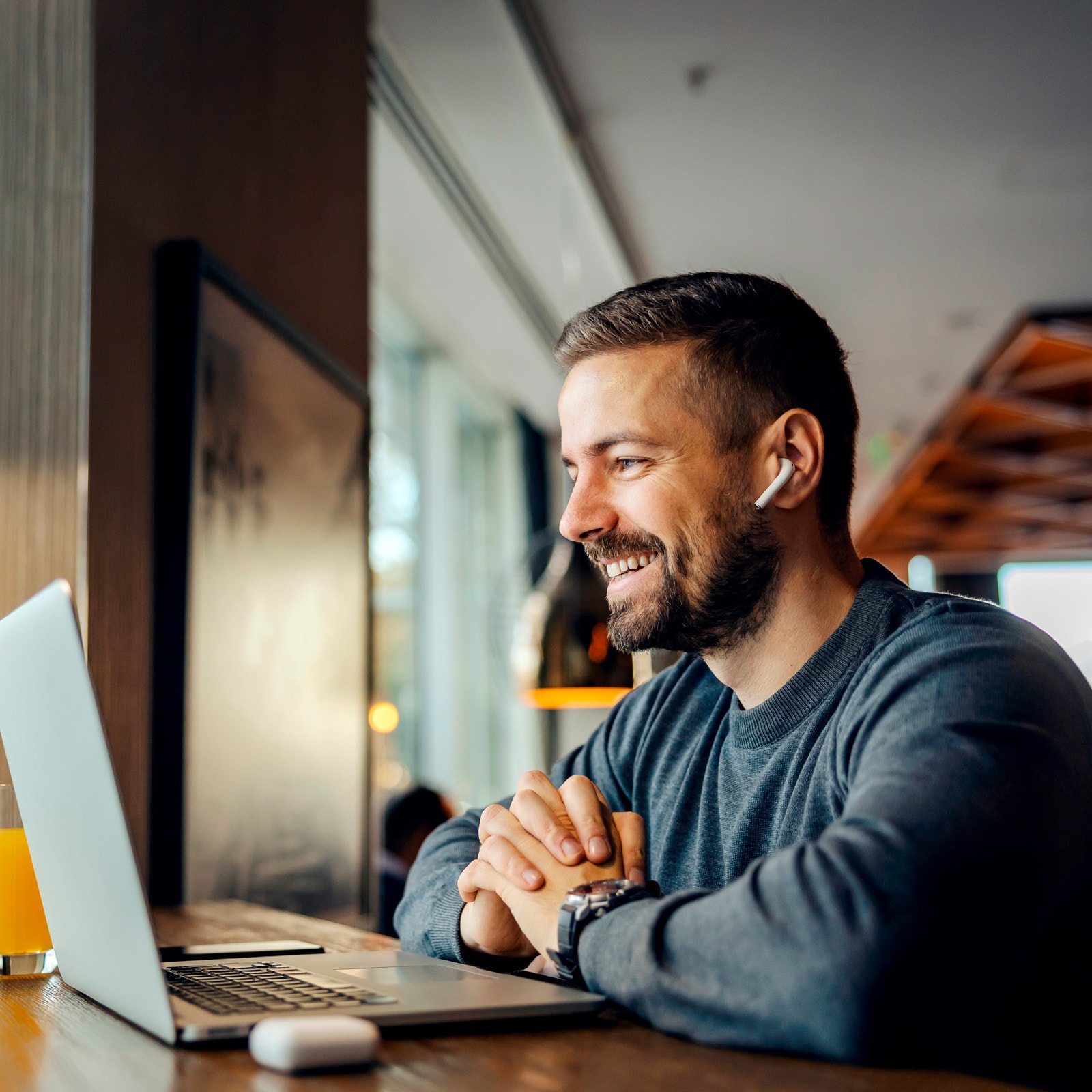 Person arbejder ved bærbar computer på café.
