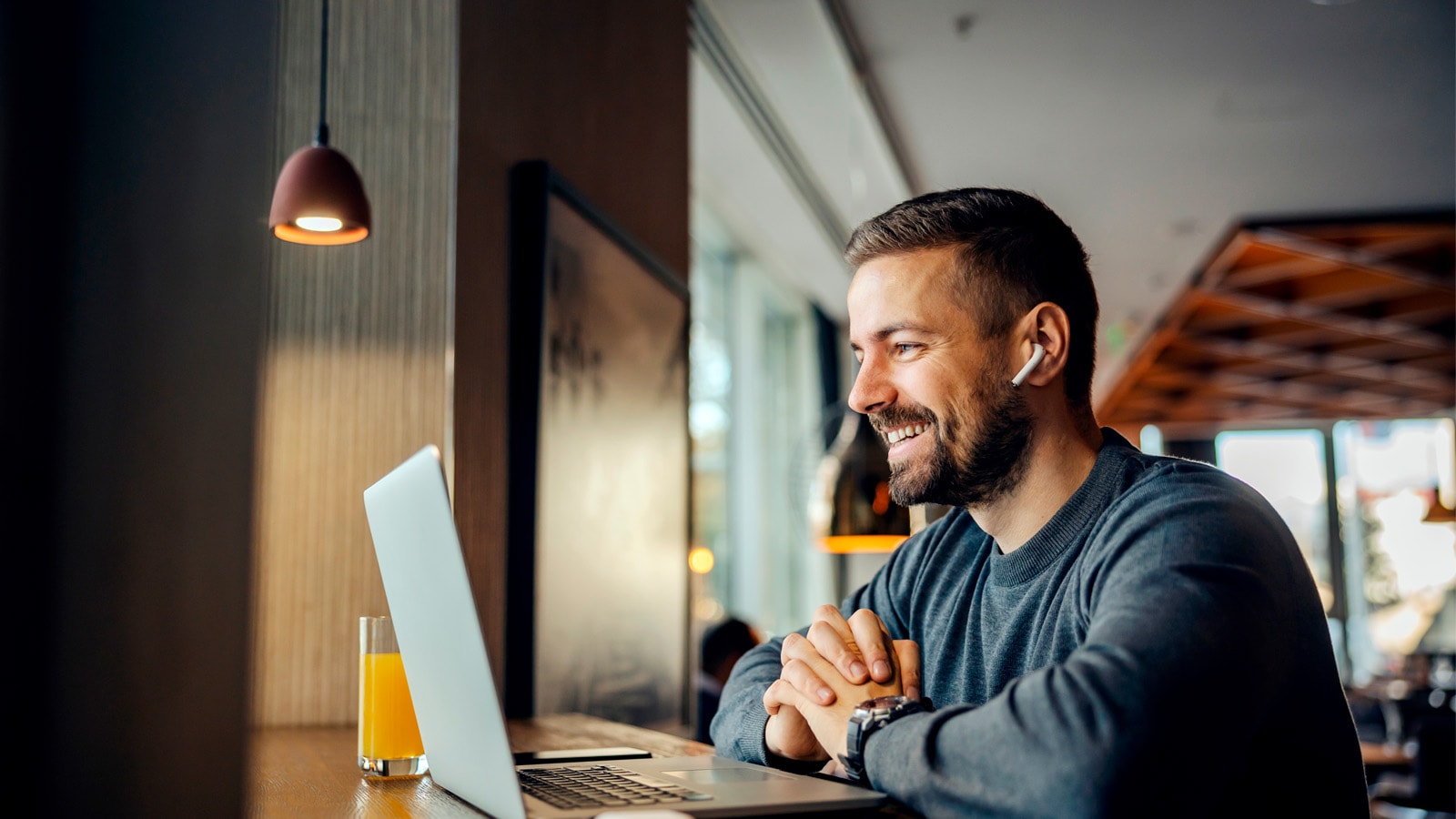 Person arbejder ved bærbar computer på café.